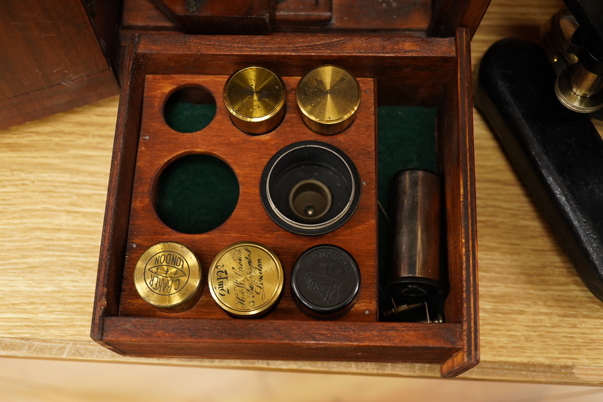 An early 20th century pine and plywood cased microscope by C.Baker, London, containing an integral drawer with alternative lenses, and a magnifying glass on a brass stand, the case dimensions; 38cm high, 18cm wide, 27.5c